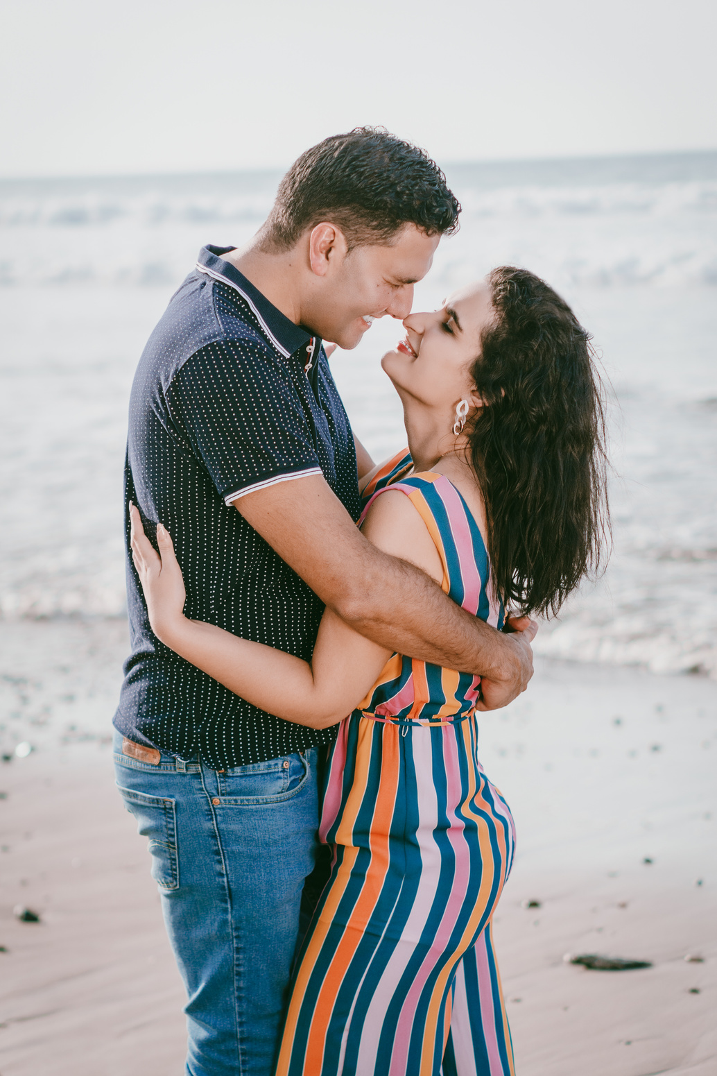 Pareja romántica de jóvenes abrazados y enamorados  frente al atardecer en el mar